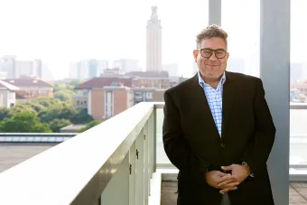 Dean Rivera-Servera stands on a Balcony overlooking the university campus.  The UT tower rises in the background.