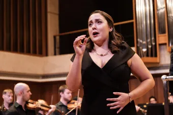A soprano sings dramatically with an orchestra behind her