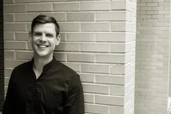 A black and white photo of Dr. Marc Sosnowchik standing in front of a brick wall, smiling.