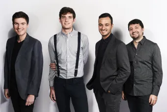 The four members of Sandbox Percussion casually standing together and smiling.