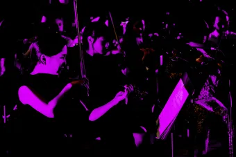 Neon purple photo of the UT New Music Ensemble in concert.