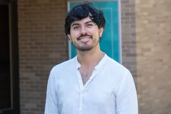 Daniel Ruiz Bustos smiling in front of a brick building