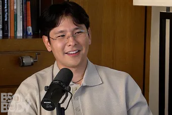 Minoo Dixon talking into a mic with a bookshelf in the background