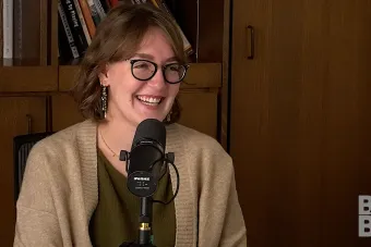 Chloe Yofan talking into a mic with a bookcase in the background