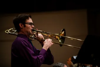Dillon MacIntyre playing the trombone with a dark background