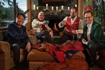 the Miro Quartet sitting around a fireplace in holiday sweaters
