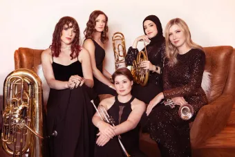 Seraph Brass sit together on and around a leather sofa, with their instruments close at hand. 