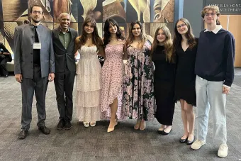 A group of 7 college students pose with their professor 