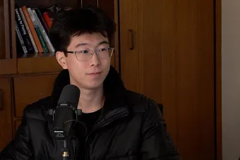Yida An talks into a mic with a bookshelf in the background