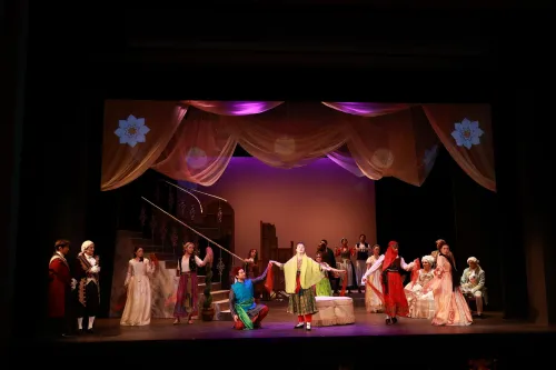 The cast of The Ghosts of Versailles in an array of colorful costumes parade across the stage. 