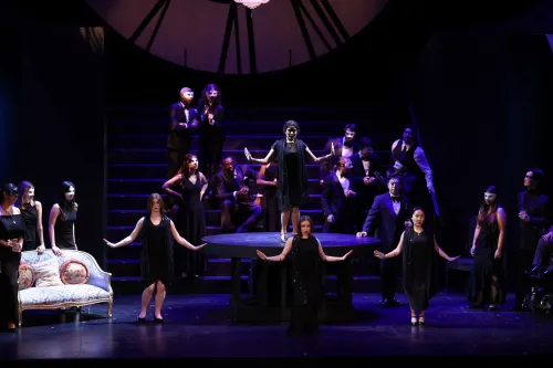 a group of women dressed in black pose with their arms out during a masquerade scene,