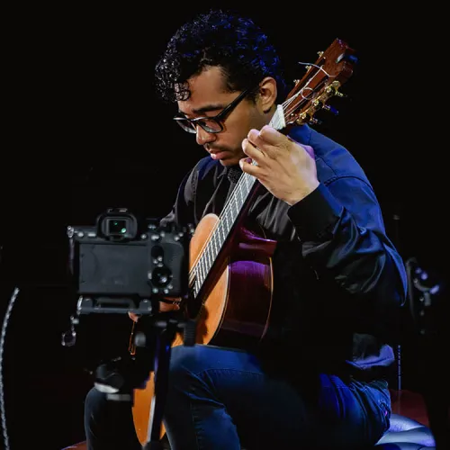 Andres Palacios performs on his guitar on stage.