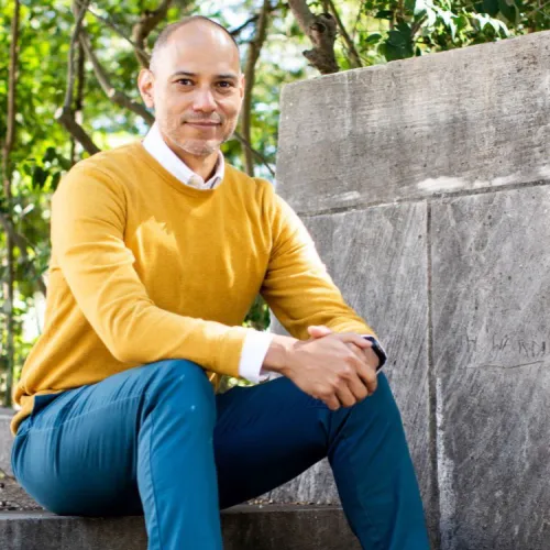 a headshot of Charles Carson, outdoors, sitting casually on a staircase.