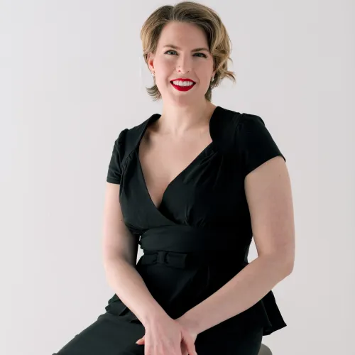 Mezzo soprano Page Stephens sits on a stool in a 40s style dress.