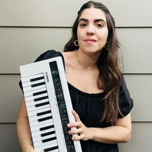 Juliana holds a Yamaha Midi Controller and smiles at the viewer.