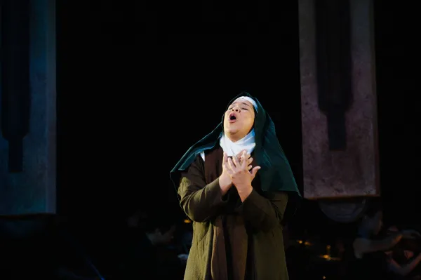 A nun holds her hands over her heart as she cries out to the heavens.