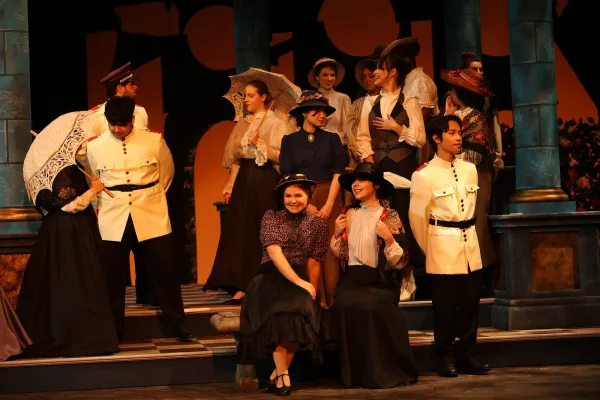 a group of singers group on stage listening to a singer perform an aria