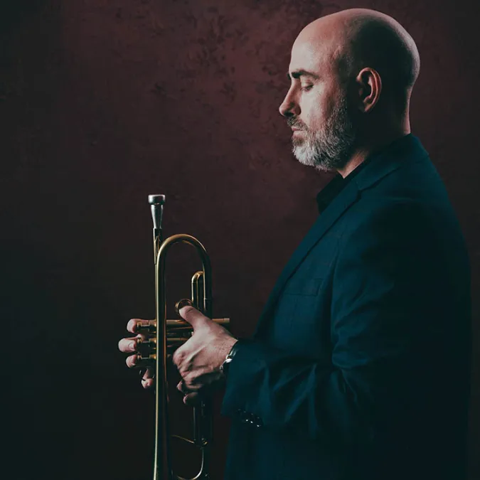 Side profile of Mike Sailors holding a trumpet with his eyes closed