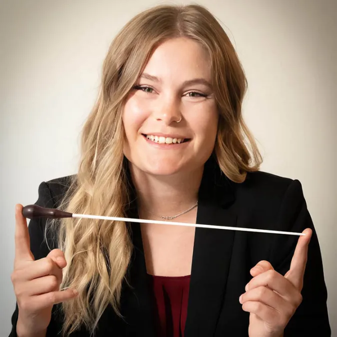 a headshot of Emily Warren holding her conducting baton