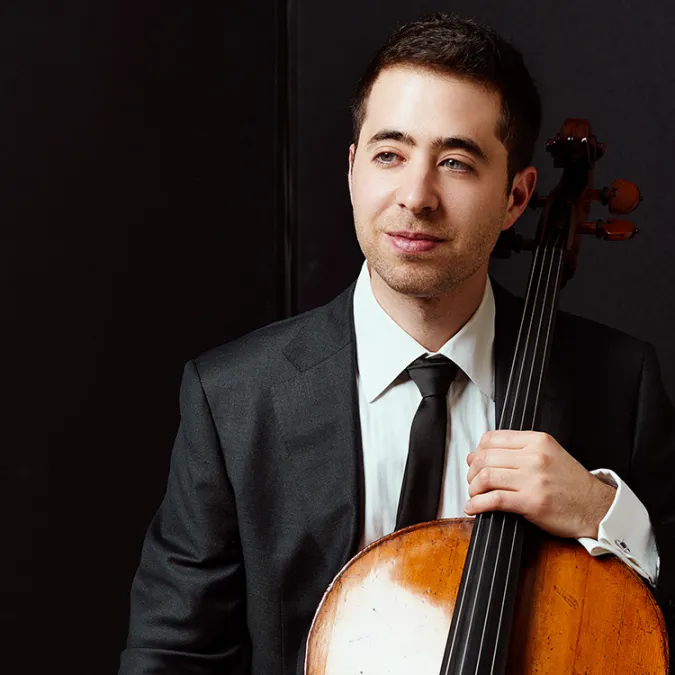 A headshot of Matthew Zalkind with his cello.