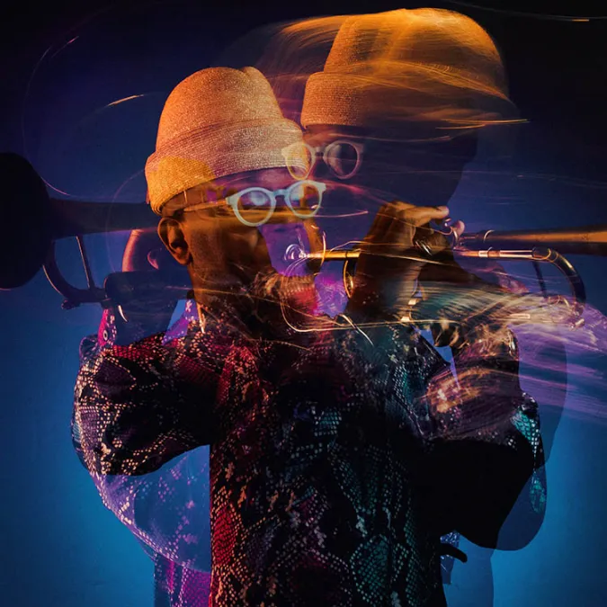 a slow-shutter image of Etienne Charles playing his trumpet captures dynamic motion as he plays.