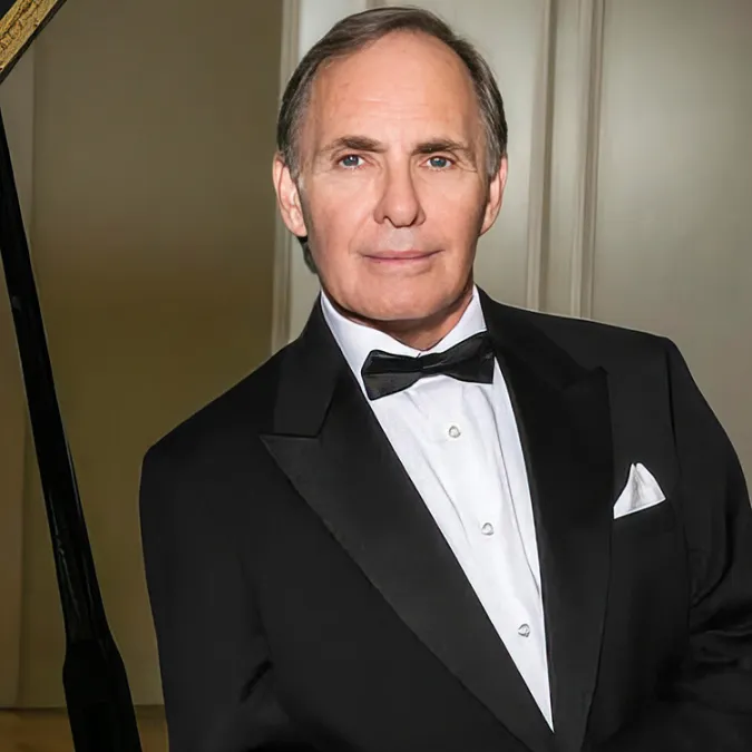 a headshot of James Dick leaning against the piano