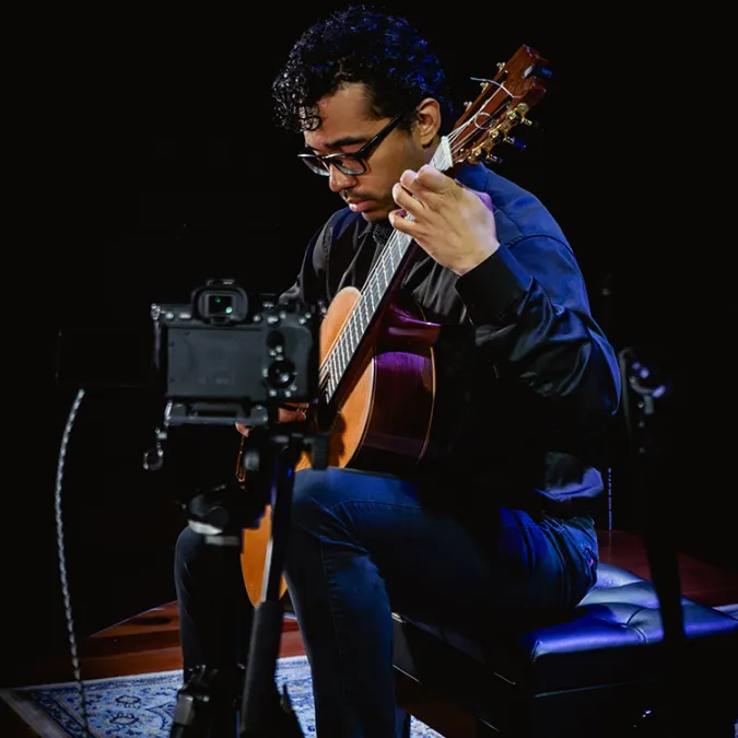 Andres Palacios performs on stage with his guitar.