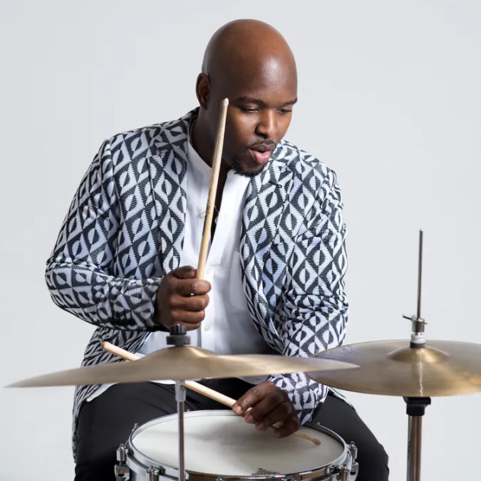 Ulysses S. owns sits at a drums set, and plays the high-hat and snare.
