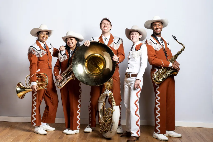 Smiling members of longhorn band pose with instruments