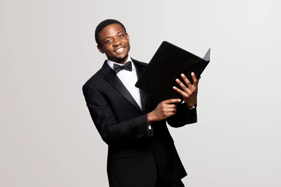 A voice student holds a music folio and smiles into camera