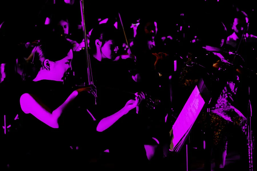 Neon purple photo of the UT New Music Ensemble in concert.
