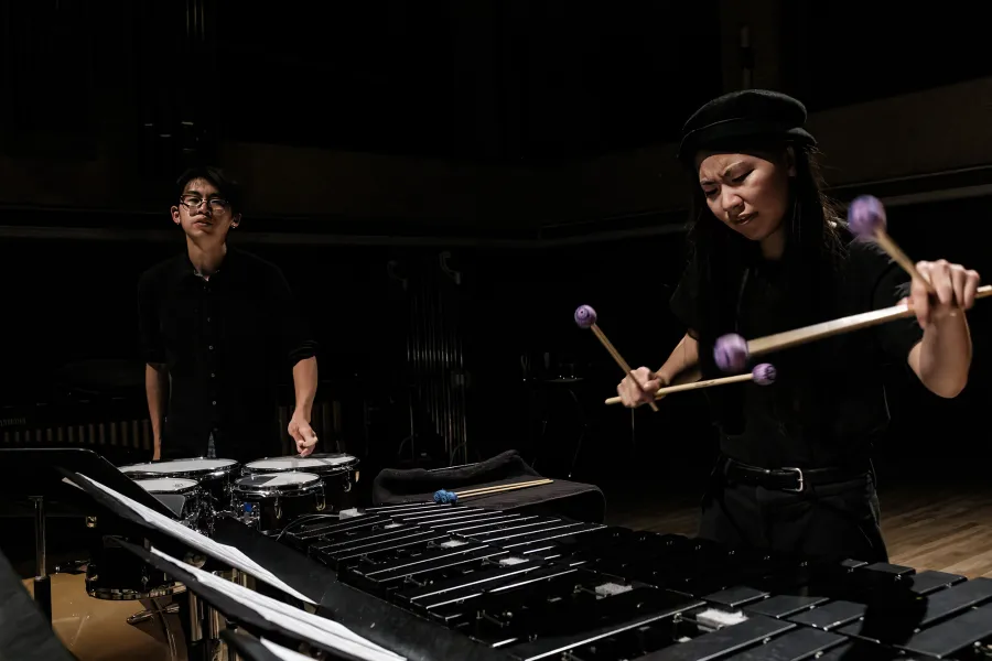 Percussion Ensemble Two students play percussion instruments in a dimly lit hall.