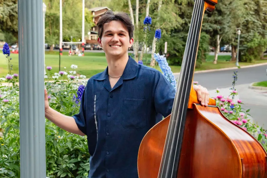 Aidan Berg standing in a park holding a standup bass