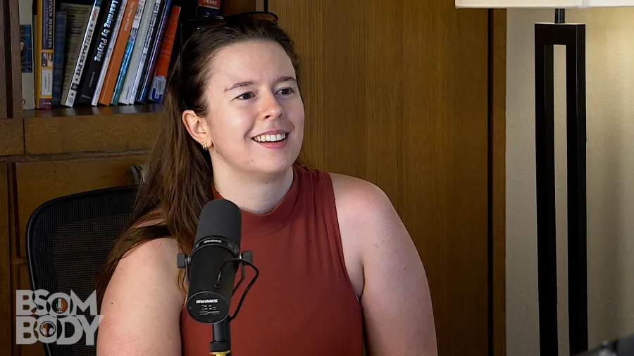 Maria Parrini sitting and talking into a mic with a bookshelf in the background