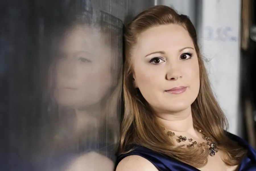 Headshot of soprano Rebecca Davis leaning against a reflective surface