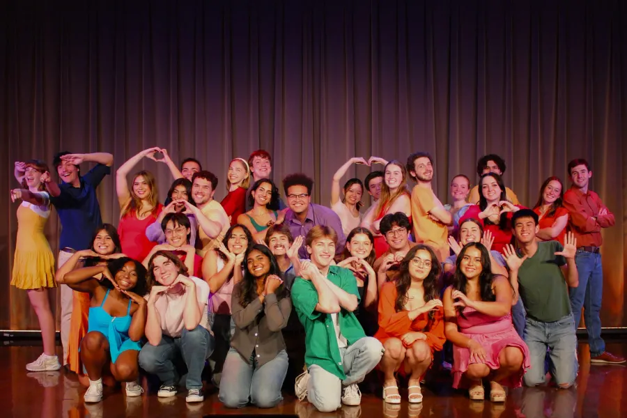 Students in The University of Texas Longhorn Singers pose in front of a stage curtain.