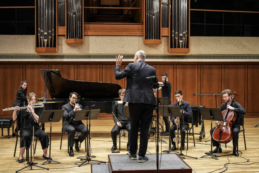 Conductor Januibe Tejera conducts seven musicians in SoundMap Ensemble on stage in Bates Recital Hall.