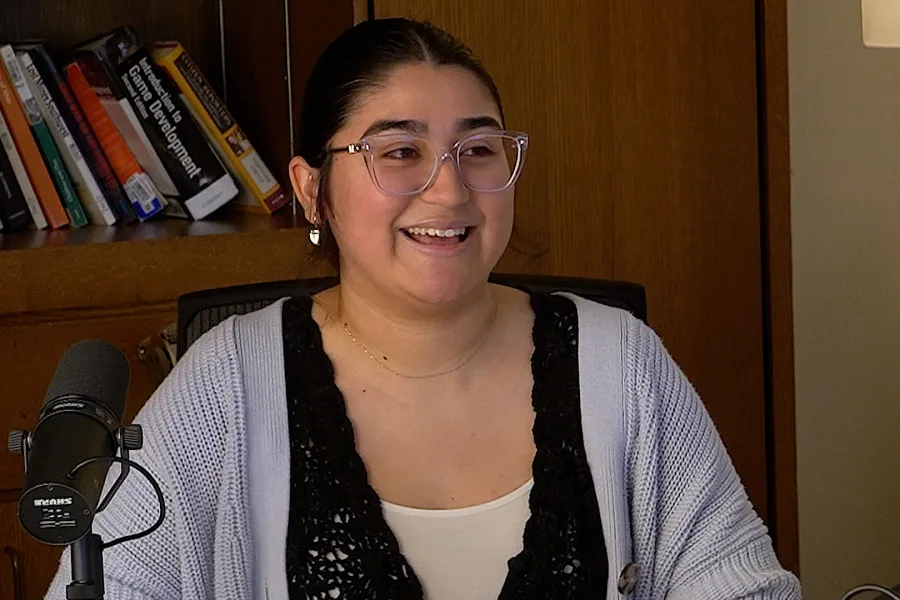 Isabella Perez talking into a mic with a bookshelf in the background