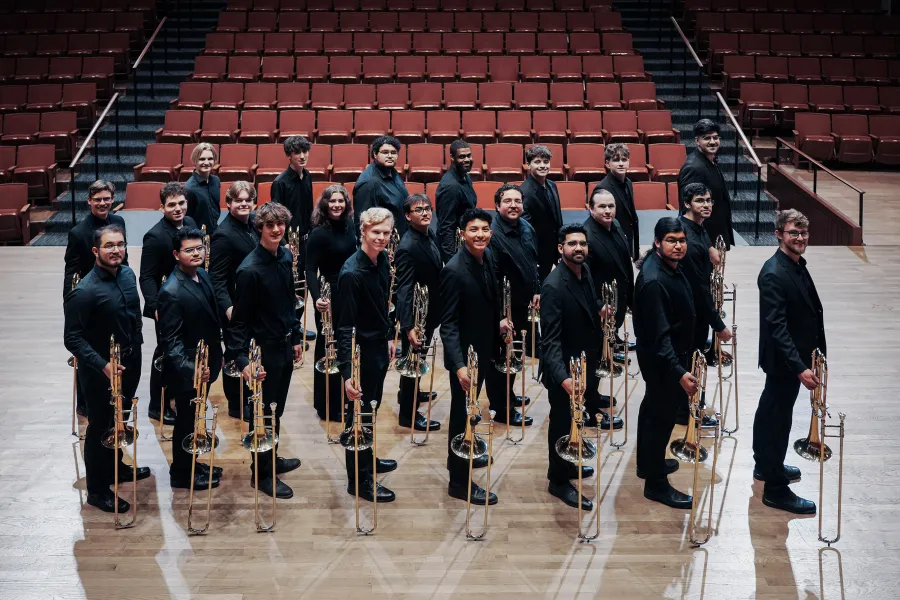 Trombone Choir on the stage of Bates Recital Hall with their trombones