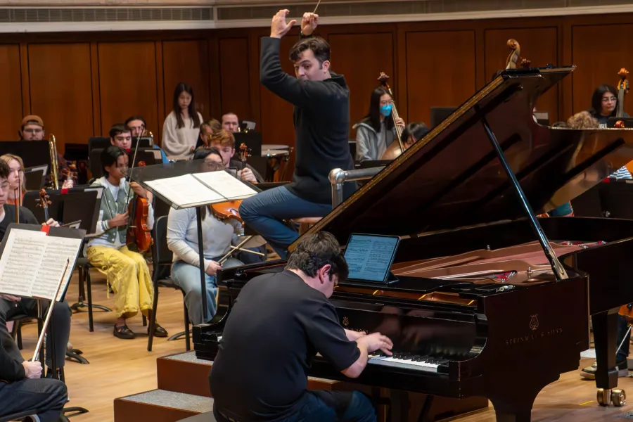 conductor  Farkhad Khudyev with Behzod Abduraimov on piano on stage in front of an orchestra
