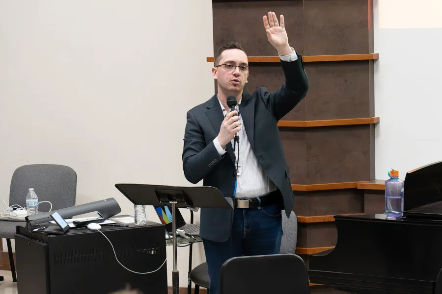 Presenter talks into a mic with a hand raised