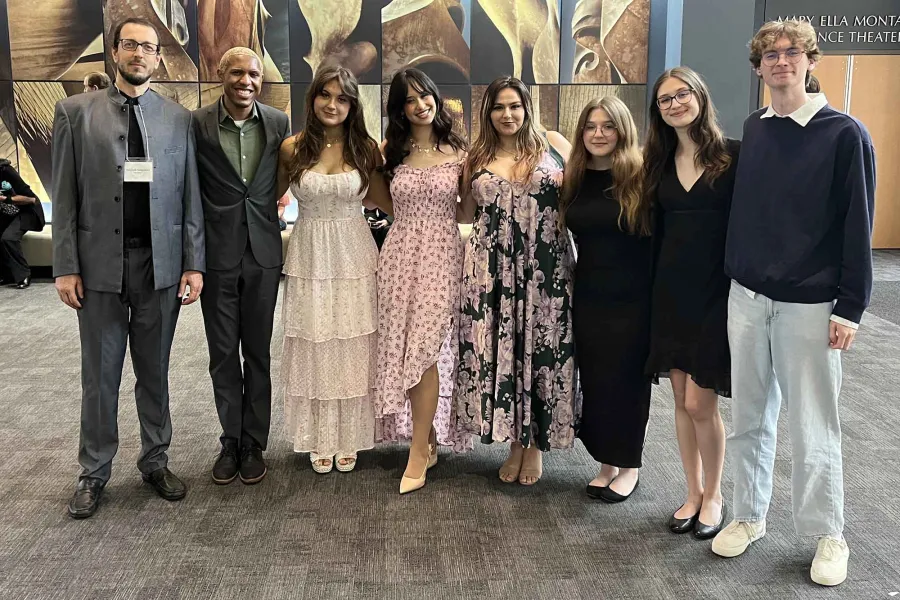 A group of 7 college students pose with their professor 