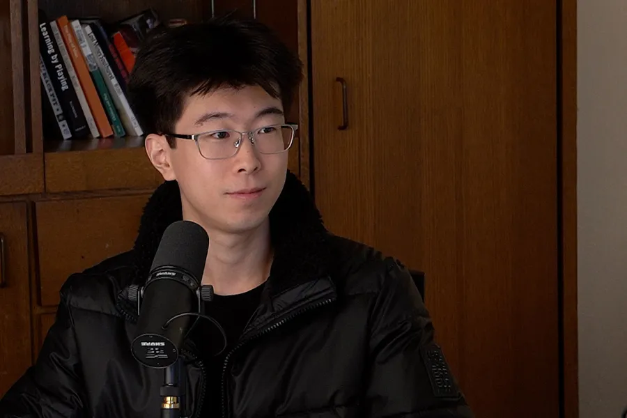 Yida An talks into a mic with a bookshelf in the background