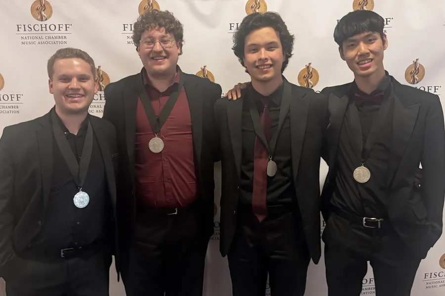 The members of 4116 Saxaphone quartet standing with medals around their neck
