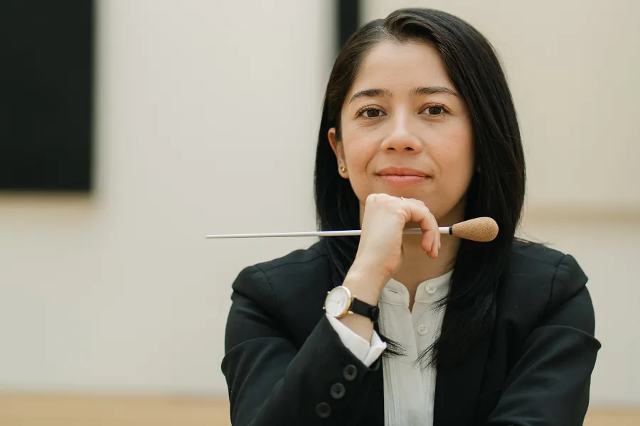 A conductor poses with a batton 