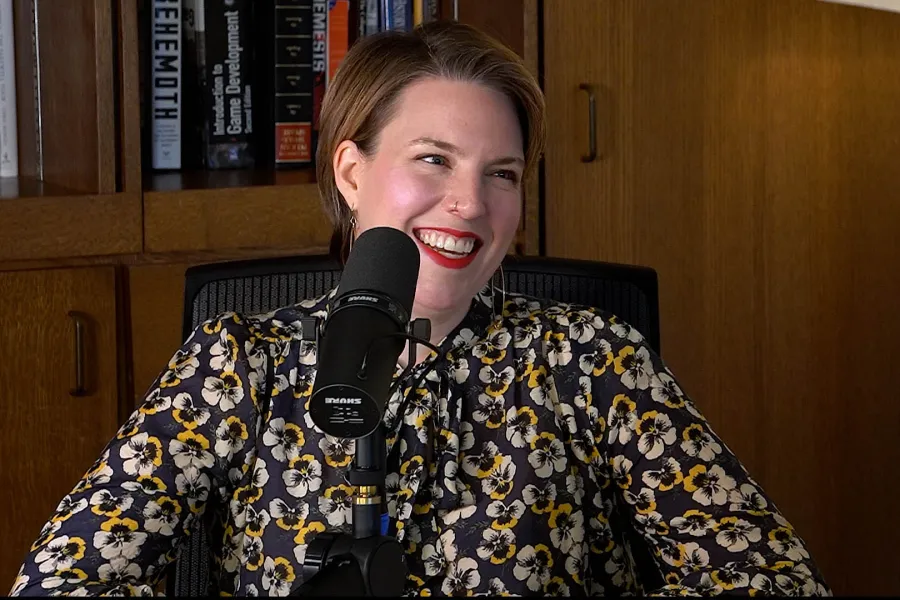 Page Stephens talking into a mic with a bookshelf in the background