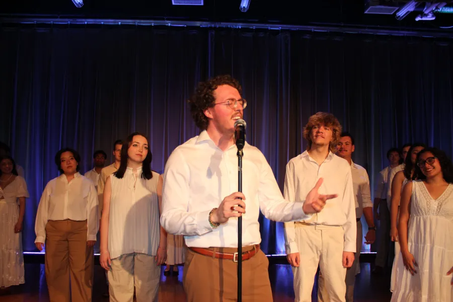a singer performs a solo on stage while other members of Longhorn singers listen behind him.