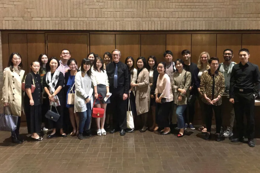 Greg Allen stands for a picture surrounded by a large group of his students.