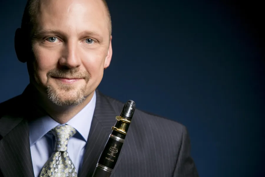 Headshot of clarinetist Jonathan Gunn wearing a suit and holding his instrument.