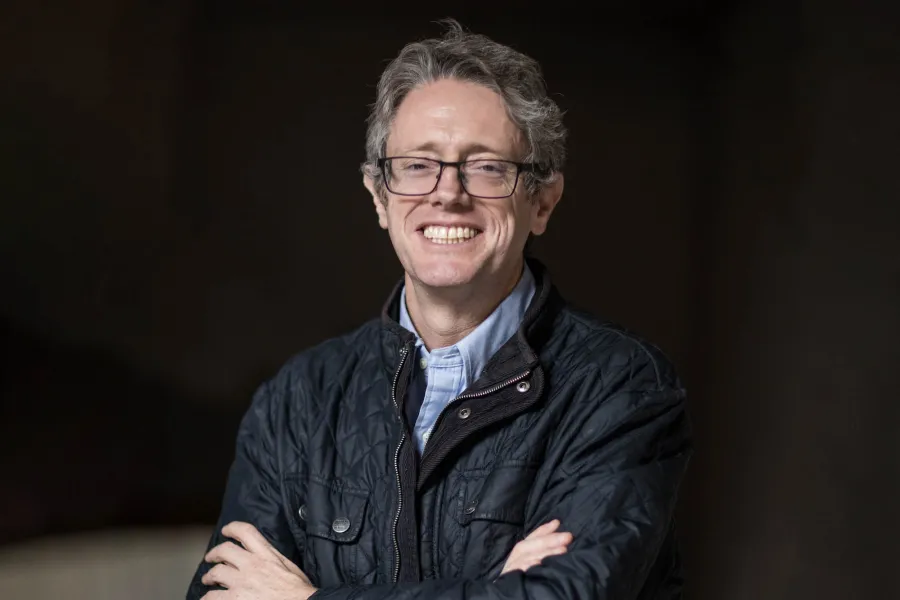Headshot of composer Rodrigo Sigal with his arms folded, smiling at the camera.
